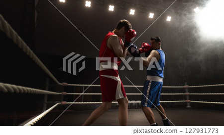 Two boxers facing off in 3D ring under dramatic lighting and smoke effects Two boxers facing off in 3D ring under dramatic lighting and smoke effects 127931773