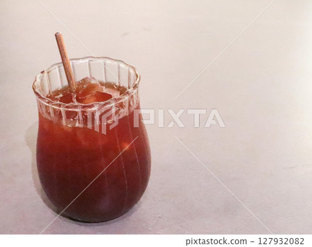 close up of a glass of iced americano with a eco friendly sugar cane straw with copy space on a white table close up of a glass of iced americano with a eco friendly sugar cane straw with copy space on a white table 127932082