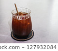 close up of a glass of iced americano with a eco friendly sugar cane straw with copy space on a white table 127932084