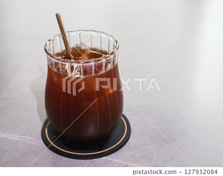 close up of a glass of iced americano with a eco friendly sugar cane straw with copy space on a white table 127932084
