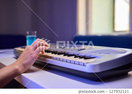 Hands play a keyboard in a modern studio, showcasing creativity and passion for music Hands play a keyboard in a modern studio, showcasing creativity and passion for music 127932121