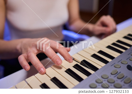 Hands play a keyboard in a modern studio, showcasing creativity and passion for music 127932133