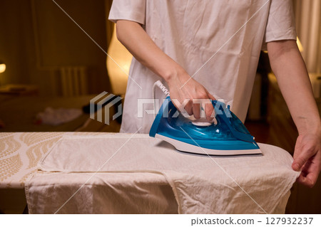 A person meticulously ironing clothes at home, ensuring all garments are neat and well cared for A person meticulously ironing clothes at home, ensuring all garments are neat and well cared for 127932237