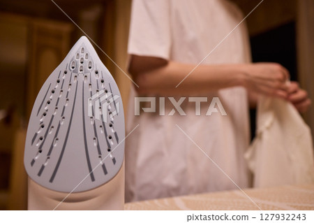 A person meticulously ironing clothes at home, ensuring all garments are neat and well cared for A person meticulously ironing clothes at home, ensuring all garments are neat and well cared for 127932243