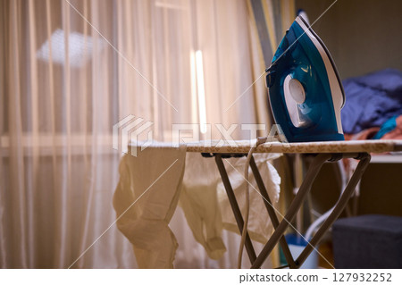 A person meticulously ironing clothes at home, ensuring all garments are neat and well cared for A person meticulously ironing clothes at home, ensuring all garments are neat and well cared for 127932252