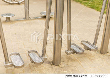 Sturdy metal fitness equipment is positioned in an outdoor park area, showcasing pedals designed for leg exercises, inviting community members to engage in physical activity Sturdy metal fitness equipment is positioned in an outdoor park area, showcasing pedals designed for leg exercises, inviting community members to engage in physical activity 127933359