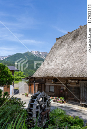 Shirakawa-go's Gassho-style houses, waterwheels, flowers and snow-capped mountains in early summer Shirakawa-go's Gassho-style houses, waterwheels, flowers and snow-capped mountains in early summer 127933553