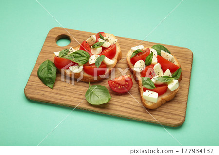 Tasty sandwich with mozzarella cheese, tomatoes and basil on cutting board. Caprese 127934132