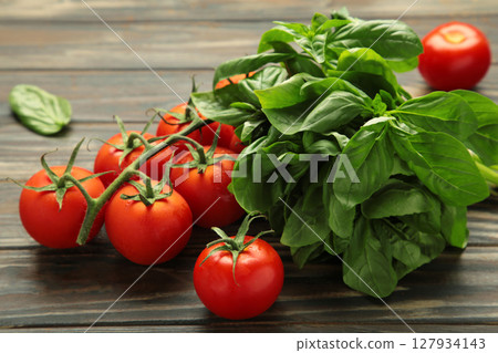 Cherry tomatoes and green basil on brown background 127934143
