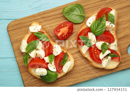 Tasty sandwich with mozzarella cheese, tomatoes and basil on cutting board. Caprese 127934151