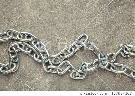 Iron chain of light metal on grey concrete background. Iron chain of light metal on grey concrete background. 127934168