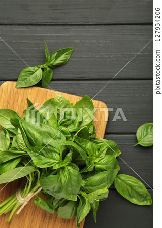 Green basil herb on cutting board on black background. Vertical photo Green basil herb on cutting board on black background. Vertical photo 127934206