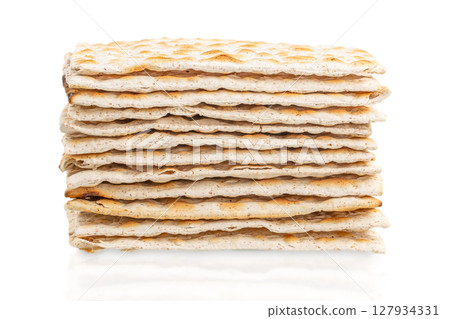 A stack of traditional matzo crackers displayed on a white background, representing Jewish culture and the observance of Shabbat and Passover 127934331