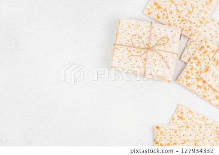 Matzo crackers neatly tied with string rest on a light textured surface, symbolizing Jewish tradition, simplicity, and the observance of Shabbat and Passover 127934332