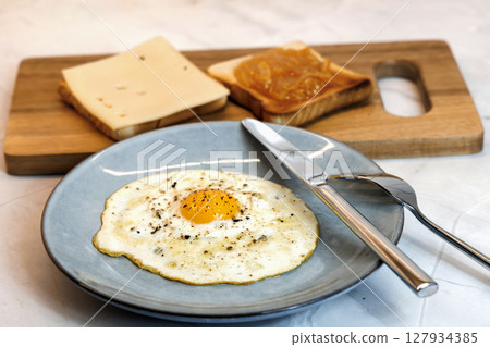 Breakfast served on the kitchen table with a fried egg on a plate and fresh bread Breakfast served on the kitchen table with a fried egg on a plate and fresh bread 127934385