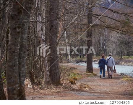 A senior couple walking along the banks of the Azusa River in Kamikochi, a popular tourist spot in spring 127934805