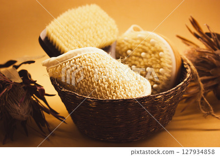 A basket of hard-bristled massage brushes. Body skin care tools concept. Beauty products. Still life with women's cosmetics and dry exotic flowers. A basket of hard-bristled massage brushes. Body skin care tools concept. Beauty products. Still life with women's cosmetics and dry exotic flowers. 127934858