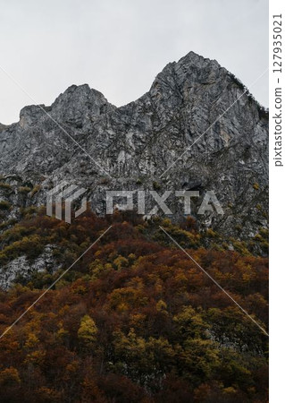 Steep rugged mountain slopes with colorful autumn trees in Prokletije National Park, Montenegro. After sunset Steep rugged mountain slopes with colorful autumn trees in Prokletije National Park, Montenegro. After sunset 127935021
