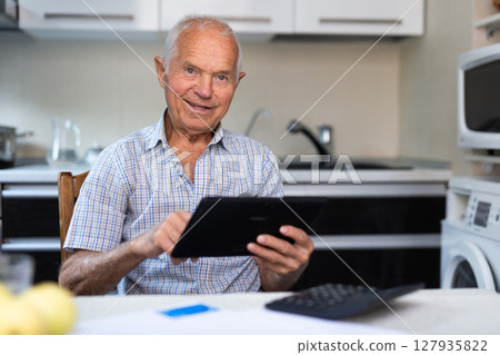 Senior man with tablet making purchases at home Senior man with tablet making purchases at home 127935822