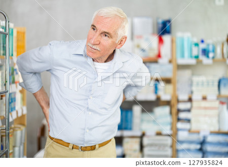 Elderly man with back pain in pharmacy Elderly man with back pain in pharmacy 127935824
