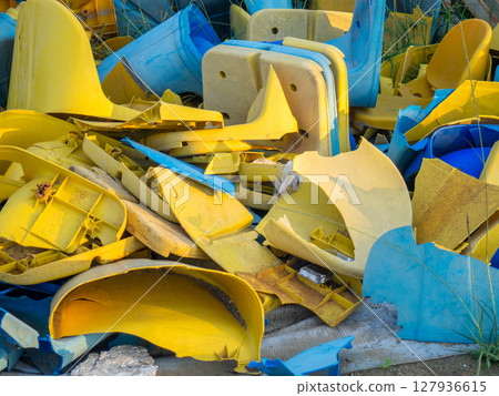 Old broken plastic chairs at the stadium. Fan riot concept. A pile of plastic chairs. 127936615