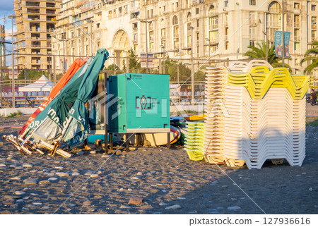 Beach equipment folded. Sunbeds on top of each other. Concept of the end of the beach season. Autumn at sea. Sunset Beach equipment folded. Sunbeds on top of each other. Concept of the end of the beach season. Autumn at sea. Sunset 127936616