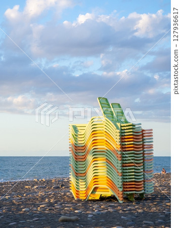 Beach equipment folded. Sunbeds on top of each other. Concept of the end of the beach season. Autumn at sea. Beach equipment folded. Sunbeds on top of each other. Concept of the end of the beach season. Autumn at sea. 127936617