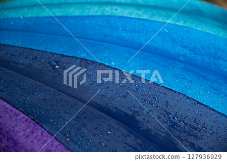 Raindrops on blue purple shades umbrella closeup wet fabric texture Raindrops on blue purple shades umbrella closeup wet fabric texture 127936929