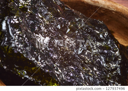 Nori chips laid out in a wooden bowl emphasizing texture and color in a cozy kitchen setting Nori chips laid out in a wooden bowl emphasizing texture and color in a cozy kitchen setting 127937496