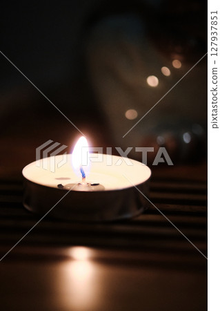 Single tea light candle burning in darkness Single tea light candle burning in darkness 127937851