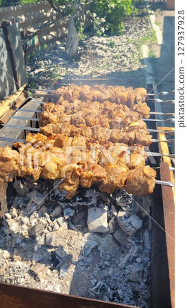 Juicy Cuts of Meat Grilling Over Charcoal in a Backyard Barbecue Setting Near the House 127937928