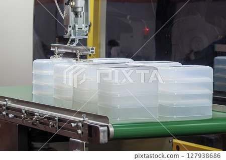 Close up scene material handling process the food container by robotic system from injection machine. Close up scene material handling process the food container by robotic system from injection machine. 127938686