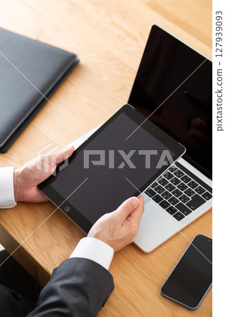 一位身穿西裝的中年男性商人在辦公桌前使用電腦工作 127939093