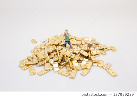 Miniature Person Standing Surrounded by Pile of Gold Bars Miniature Person Standing Surrounded by Pile of Gold Bars 127939289