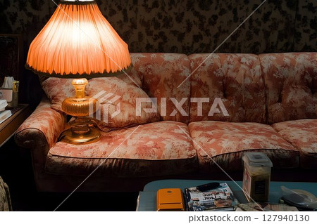 Vintage floral sofa with table lamp in dimly lit room 127940130
