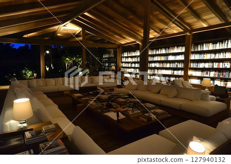 Warm lit library interior with wooden beams and comfortable seating 127940132