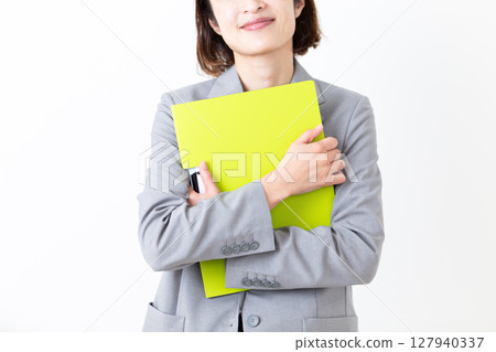 A middle-aged woman in a suit smiling while holding a file 127940337