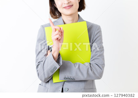 一位身著西裝的中年婦女拿著文件，用食指指著 127940382