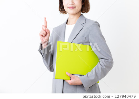一位身著西裝的中年婦女拿著文件，用食指指著 127940479