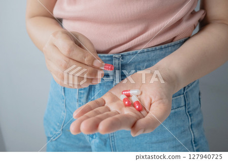Close up woman hand holding red and white tablet pill on hand. 127940725