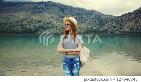 Happy young woman tourist standing on lake with mountains background. Greece, island Crete 127940745