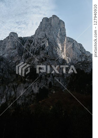 Sharp ridges and colorful forested slopes of the Prokletije mountains in autumn, captured in warm light under a clear blue sky. Nature of Montenegro 127940910