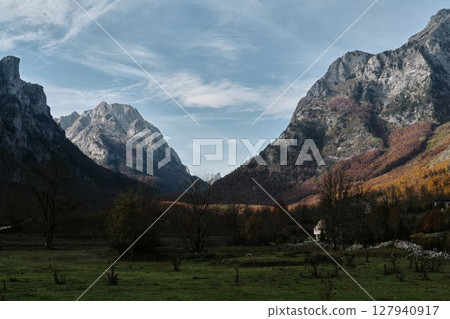 A scenic view of dramatic mountains and a remote valley in Prokletije National Park, Montenegro, during autumn with golden trees and blue sky A scenic view of dramatic mountains and a remote valley in Prokletije National Park, Montenegro, during autumn with golden trees and blue sky 127940917