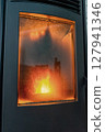 Vertical shot of a modern pellet stove in full operation with a large flame and a very dirty door window. Renewable and sustainable energy, ecological heat. 127941346