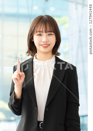 A smiling woman/businesswoman pointing with her index finger up A smiling woman/businesswoman pointing with her index finger up 127941448