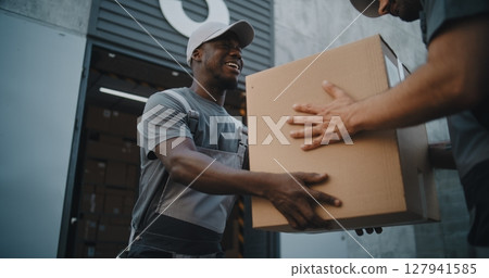 Logistics Retail Warehouse: Employee Giving Cardboard Box to Loader, Looking at Camera 127941585