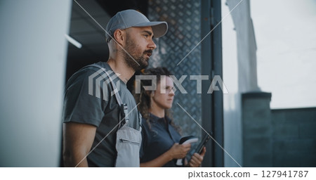 Male Worker and Female Manager with Tablet Computer Standing Outside of Logistics Retail Warehouse Male Worker and Female Manager with Tablet Computer Standing Outside of Logistics Retail Warehouse 127941787
