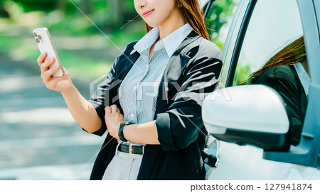女人靠在車上看著她的智慧型手機 女人靠在車上看著她的智慧型手機 127941874