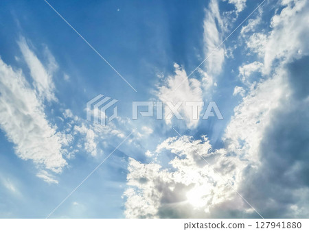 Expansive blue sky with dramatic cloud formations and sunlight breaking through the atmosphere 127941880