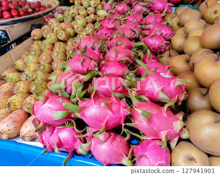 Vibrant display of exotic fruits including dragon fruit and pears at a bustling market 127941901